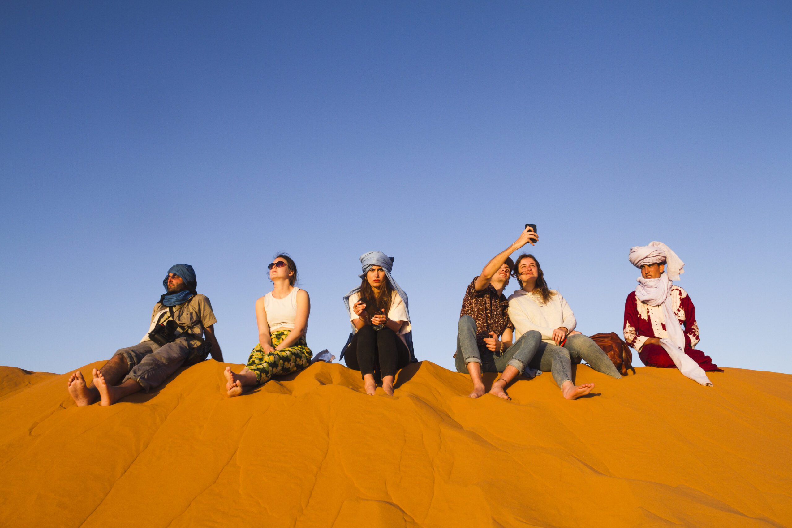group-people-sitting-top-dune - Travheir